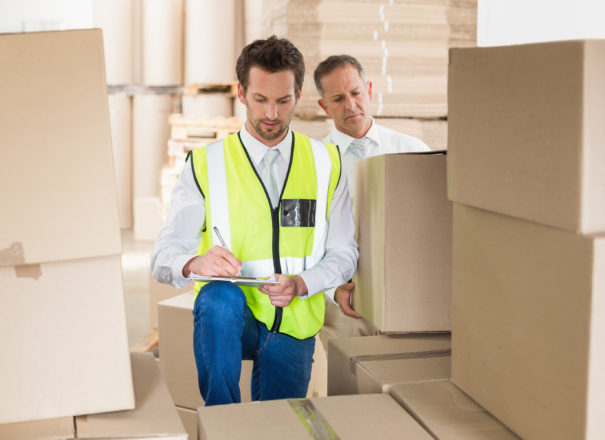 Delivery driver checking his list on clipboard in a large warehouse