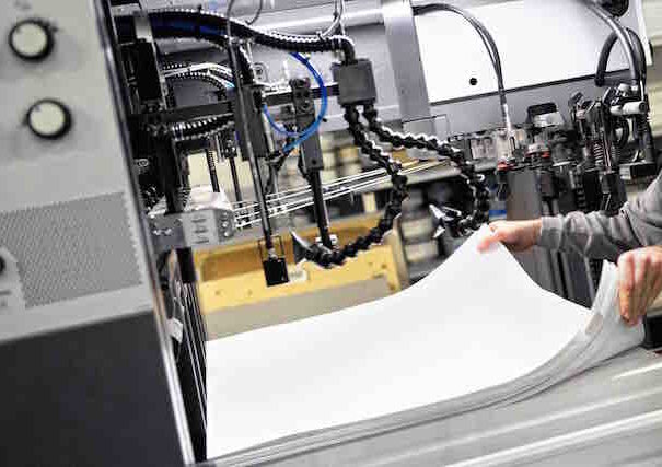 Worker Preparing Large White Papers for Print at the Printing Machine